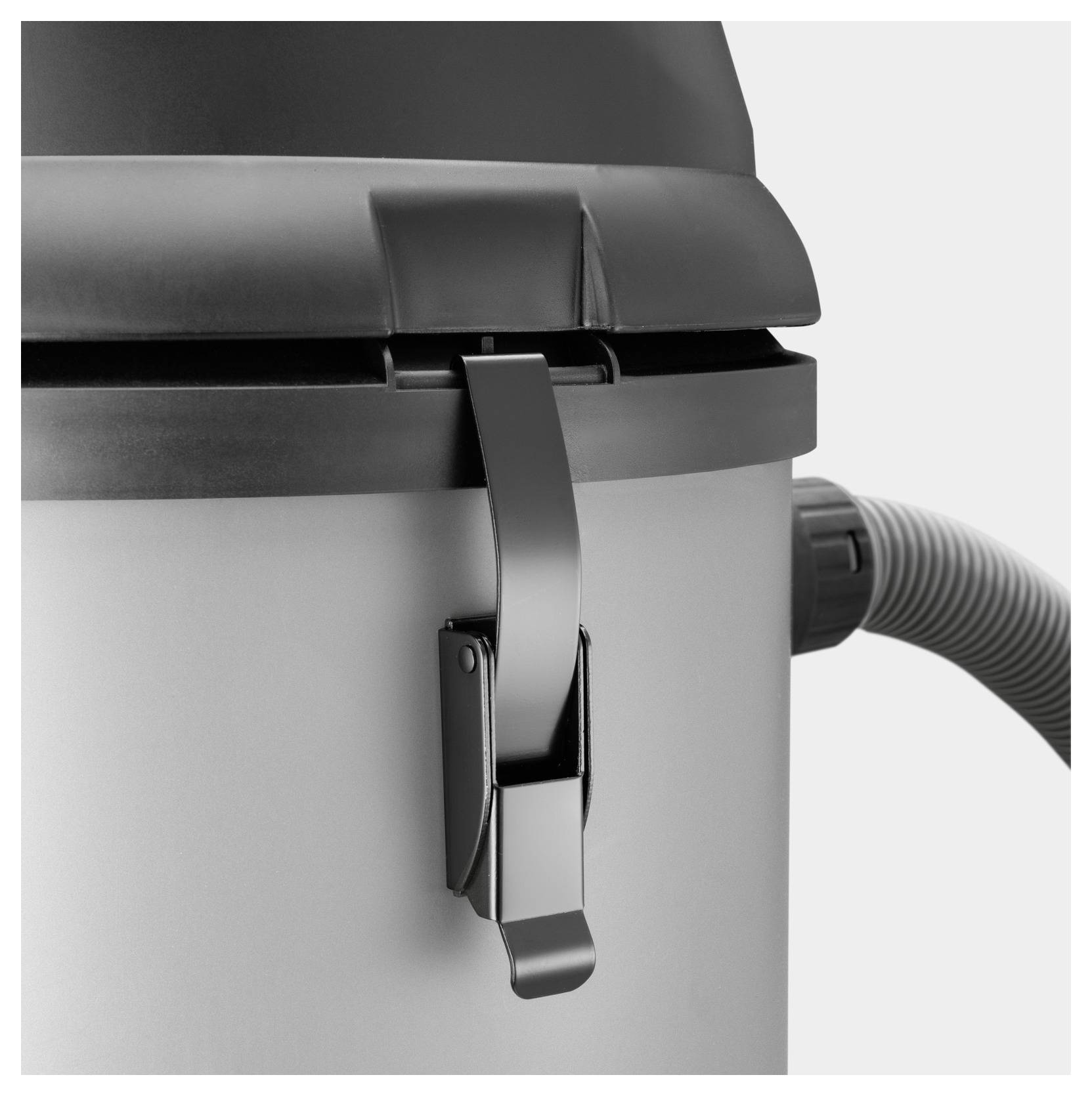 A close-up of a black latch on a cylindrical container, possibly part of a vacuum or similar device, with a hose connected on the side.