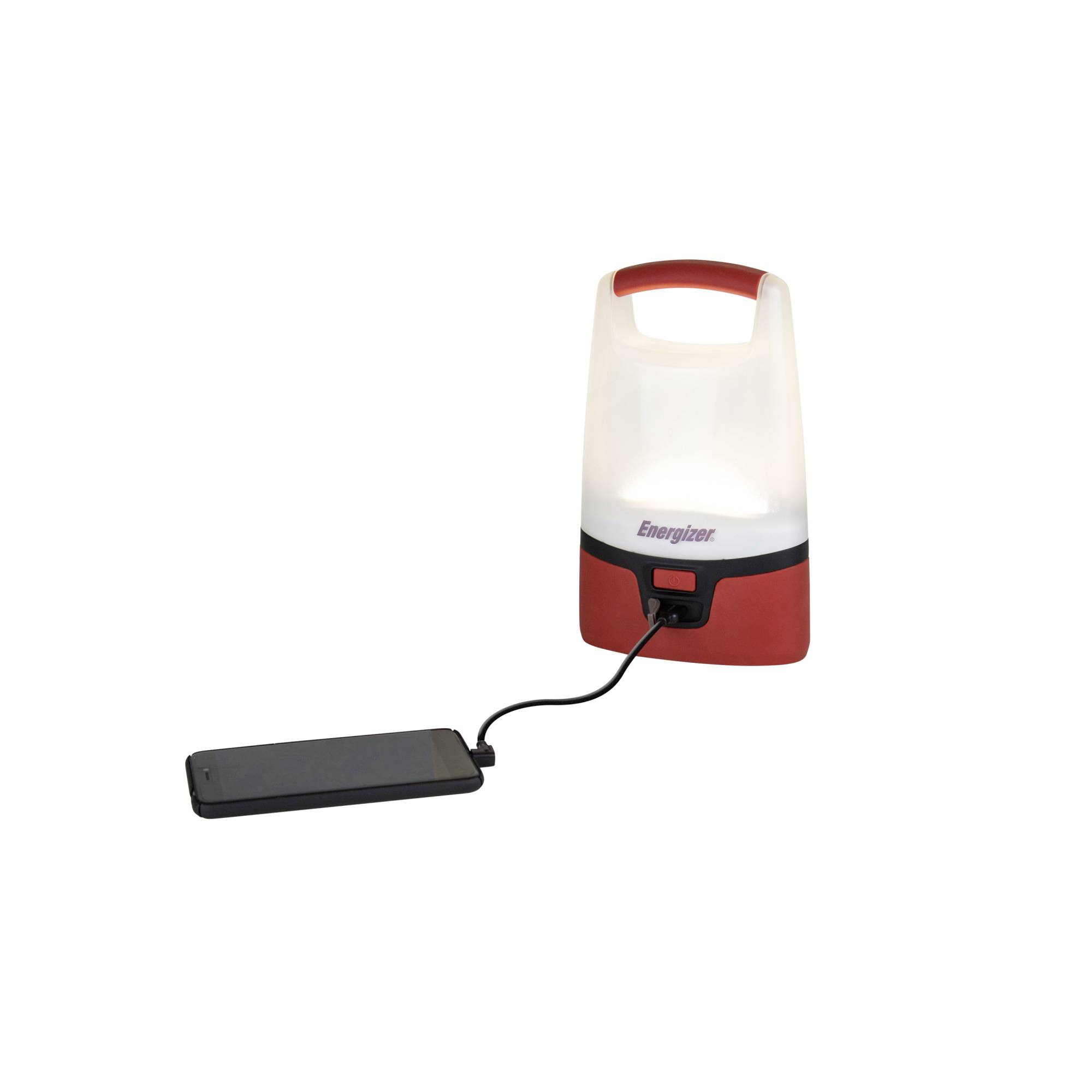 A portable lantern with a red and white casing charges a smartphone via a cable.