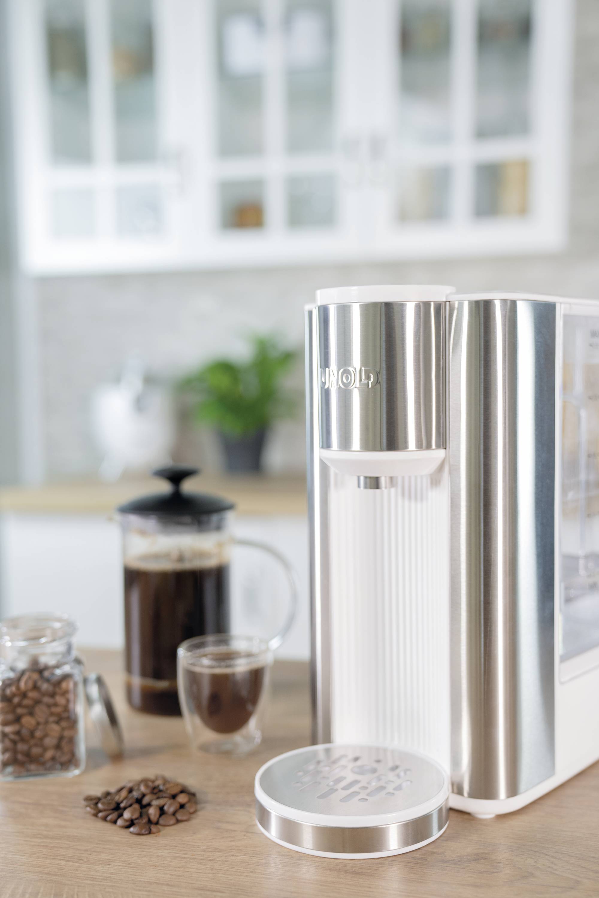 A coffee machine on a kitchen worktop next to a cafetière, a glass of coffee beans, and a cup of coffee.
