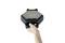 A hand is holding a black, hexagonal waffle iron with a green light on its top surface.