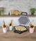 A bubble waffle iron with golden-brown waffles. Beside it, three finished bubble waffles in colourful cups, filled with fruits and sweets.