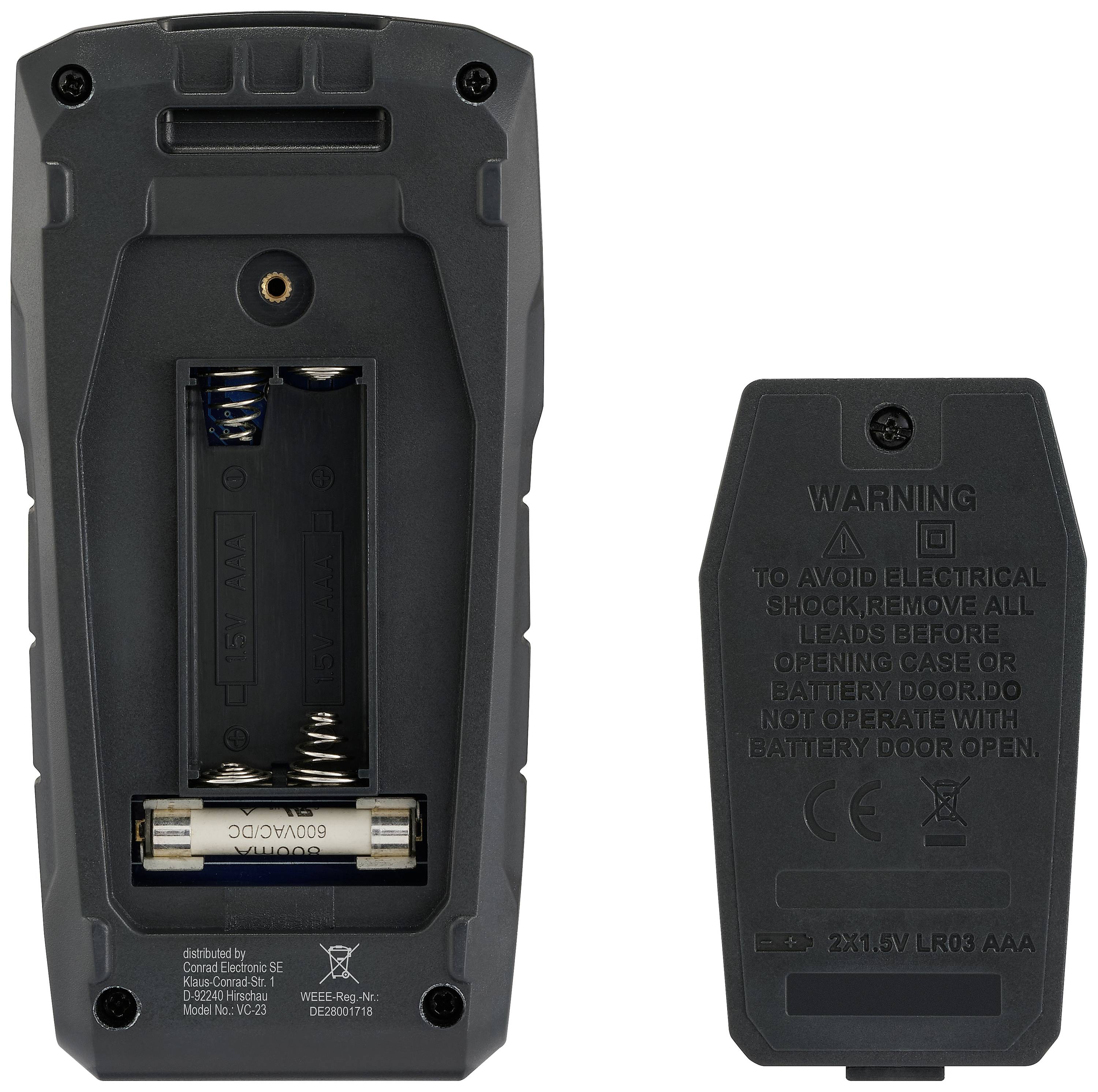 An open battery compartment on the left side shows two AA batteries and the spring mechanism. On the right side is the cover with warning notices.