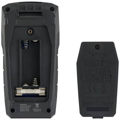An open battery compartment on the left side shows two AA batteries and the spring mechanism. On the right side is the cover with warning notices.