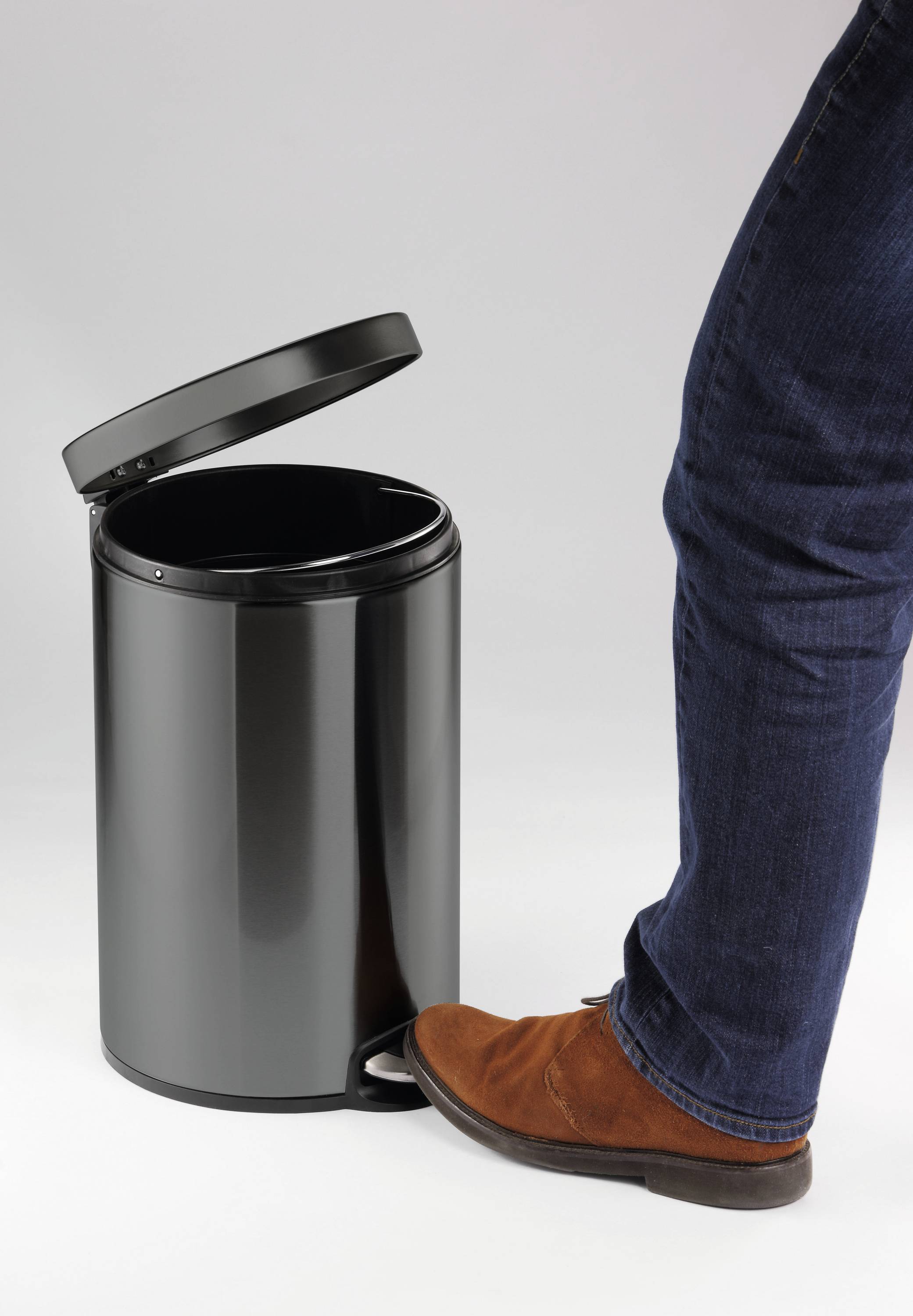 'Man opens a black pedal bin with his foot'