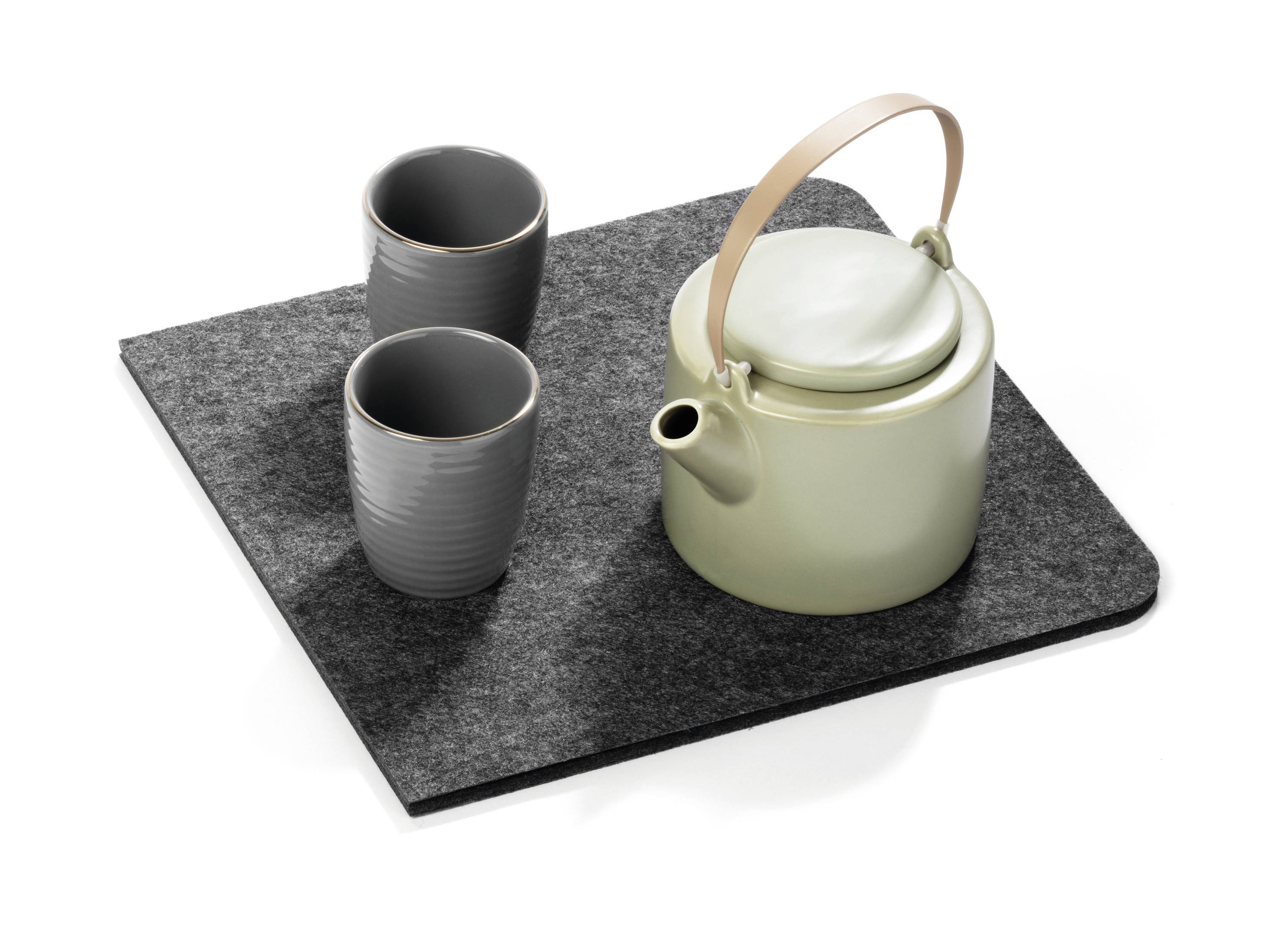 A green tea kettle with a wooden handle and two grey tea mugs on a grey felt coaster.