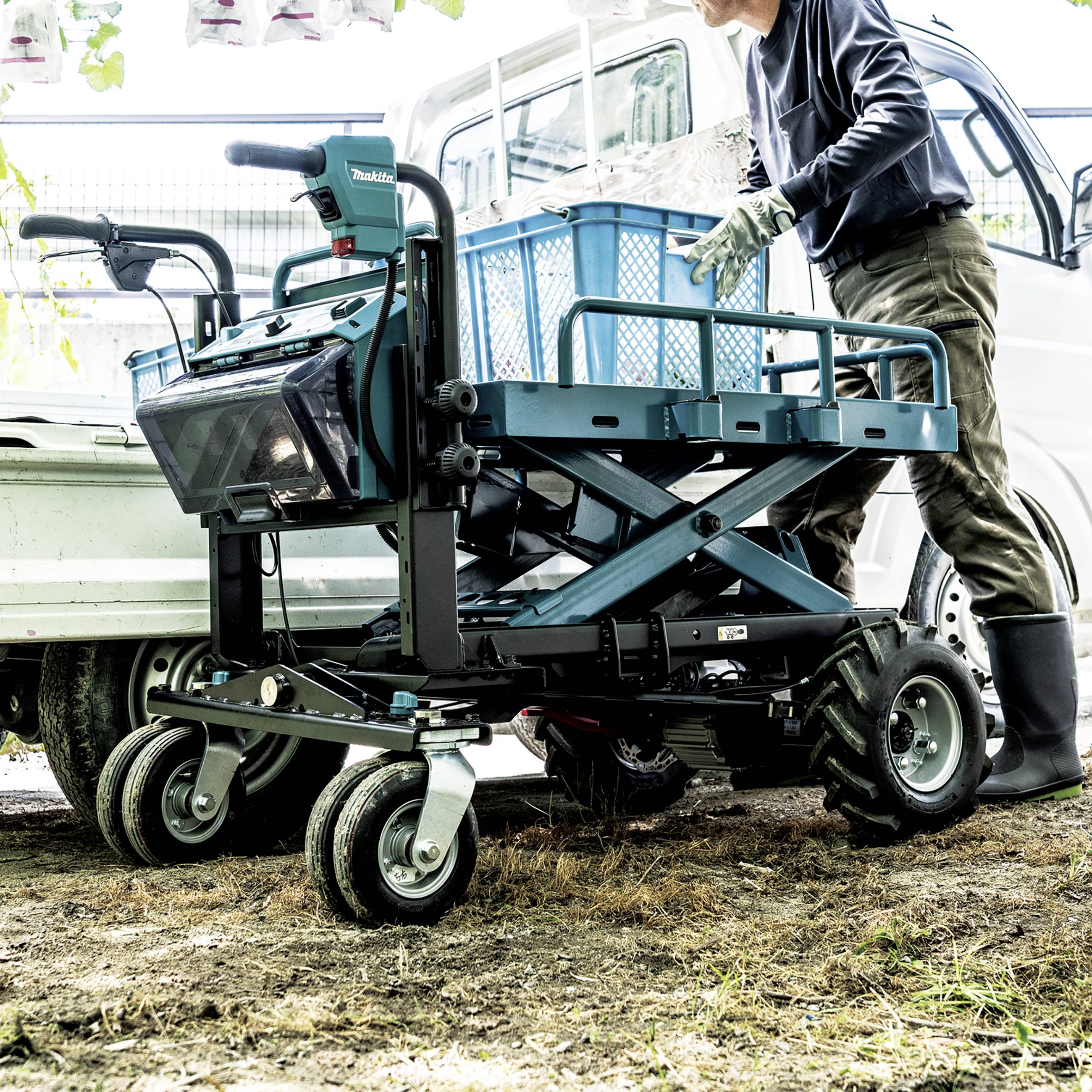 A person is loading a blue lorry with a metal basket on folding wheels. A white vehicle can be seen in the background.