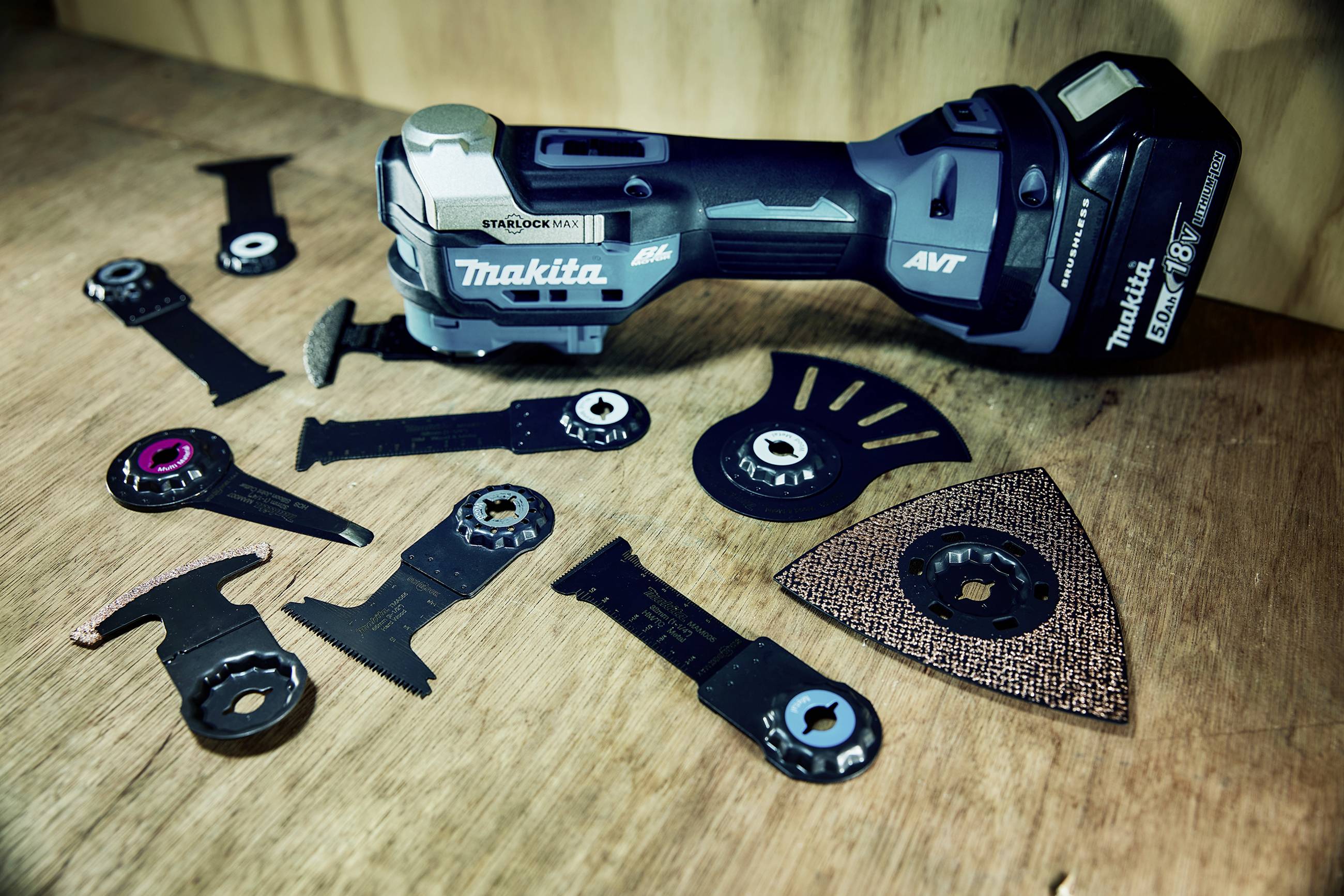 A blue Makita multi-tool grinder lies on a wooden table, surrounded by various grinding and cutting attachments.