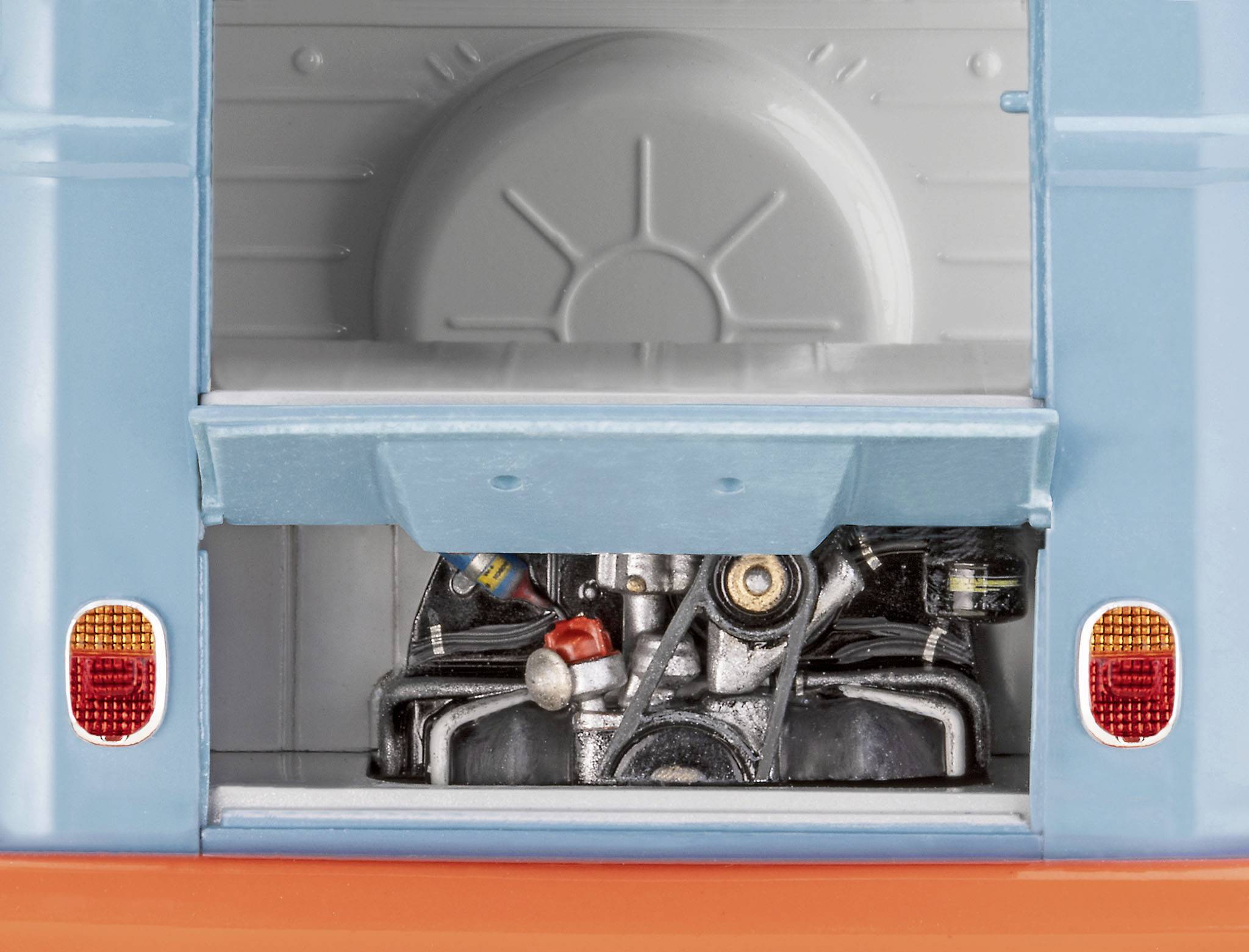 An open boot of a classic minibus reveals the engine. The blue and orange parts of the vehicle are visible.