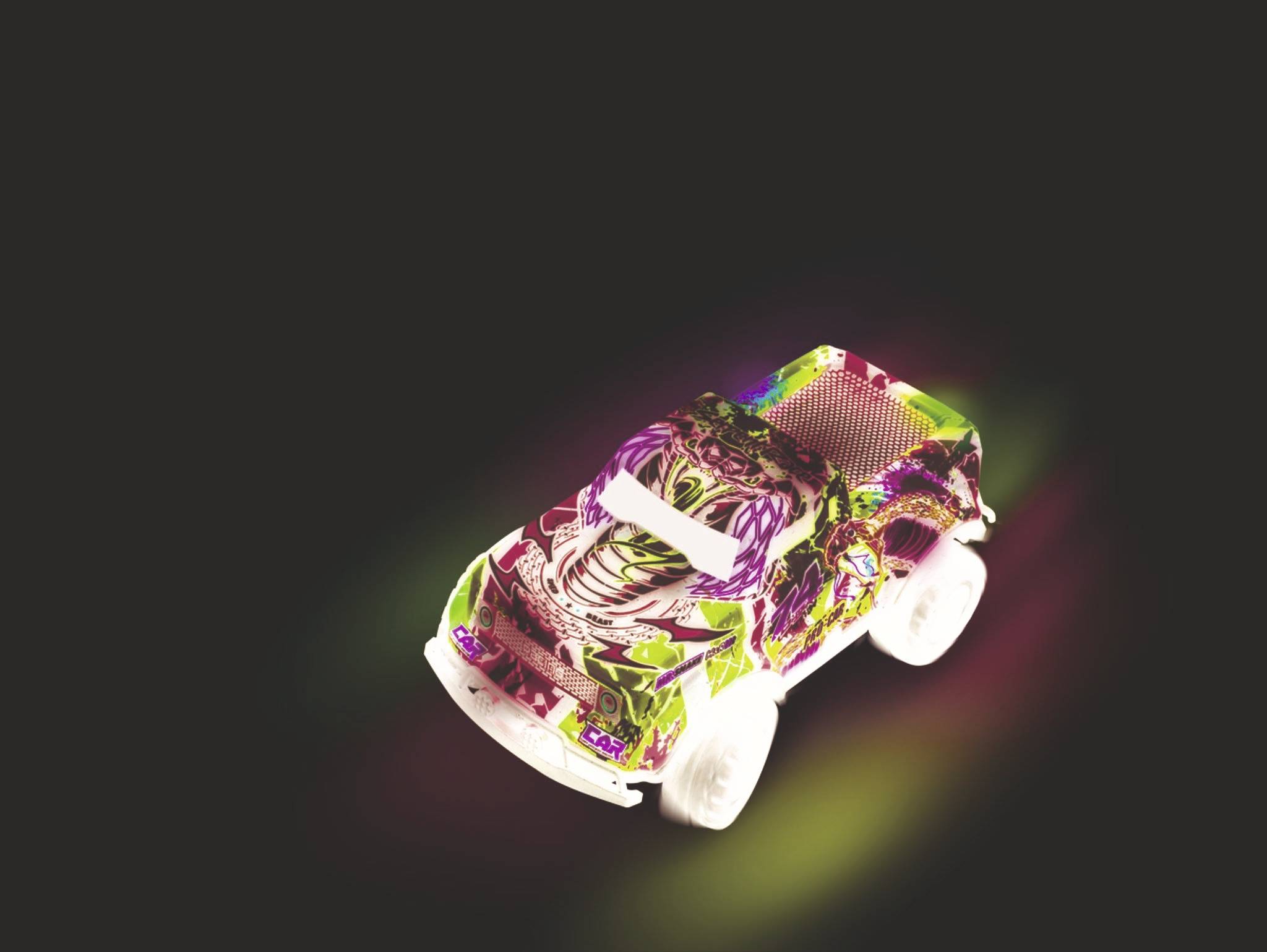 Toy car against a black background, decorated with colourful stickers.