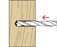 A drill bit enters a piece of wood from the right. A red arrow indicates the drill's rotational direction to the left.