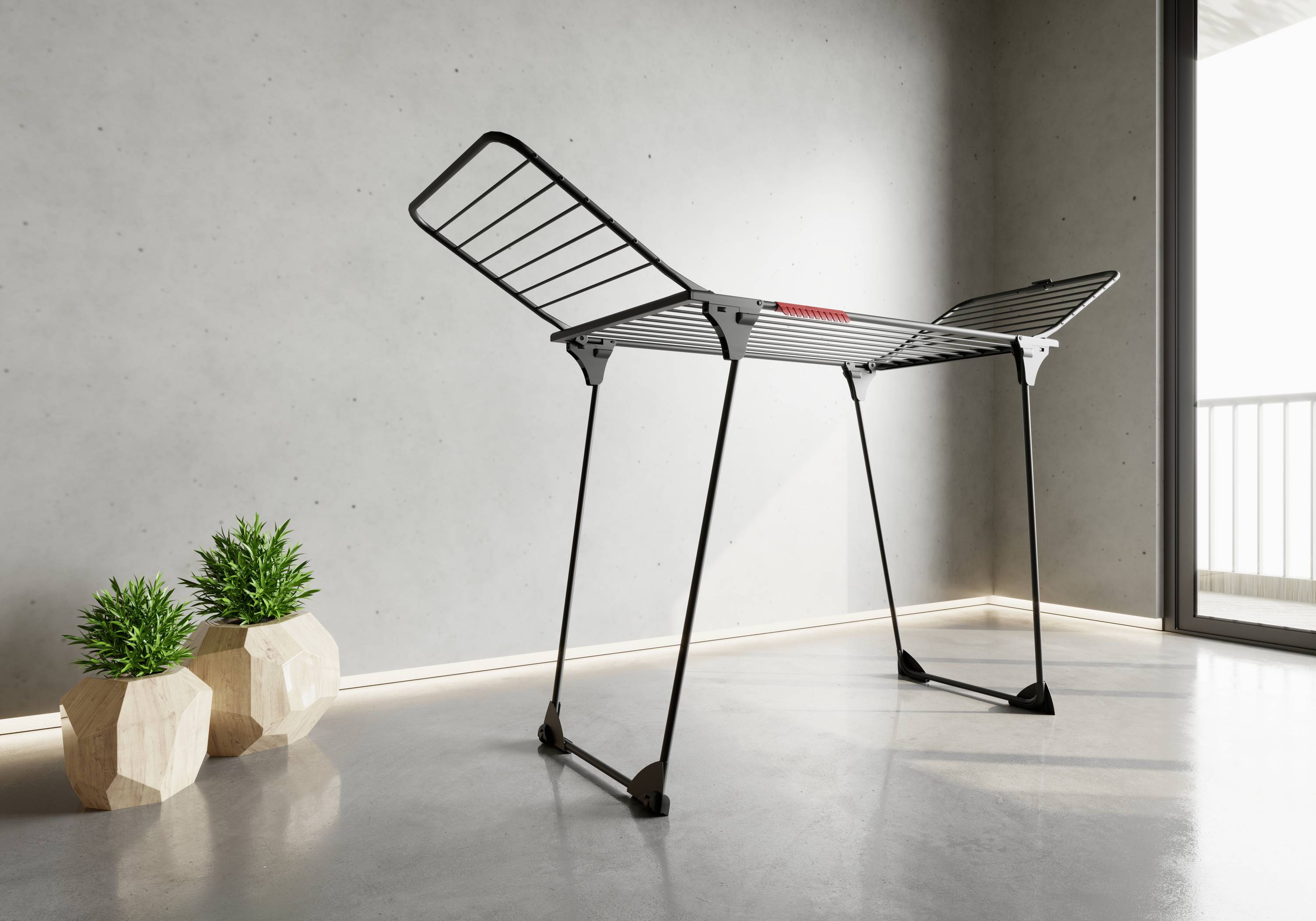 Coat stand in a modern, minimalist space, with grey walls and potted plants. Light streams in from a balcony window.