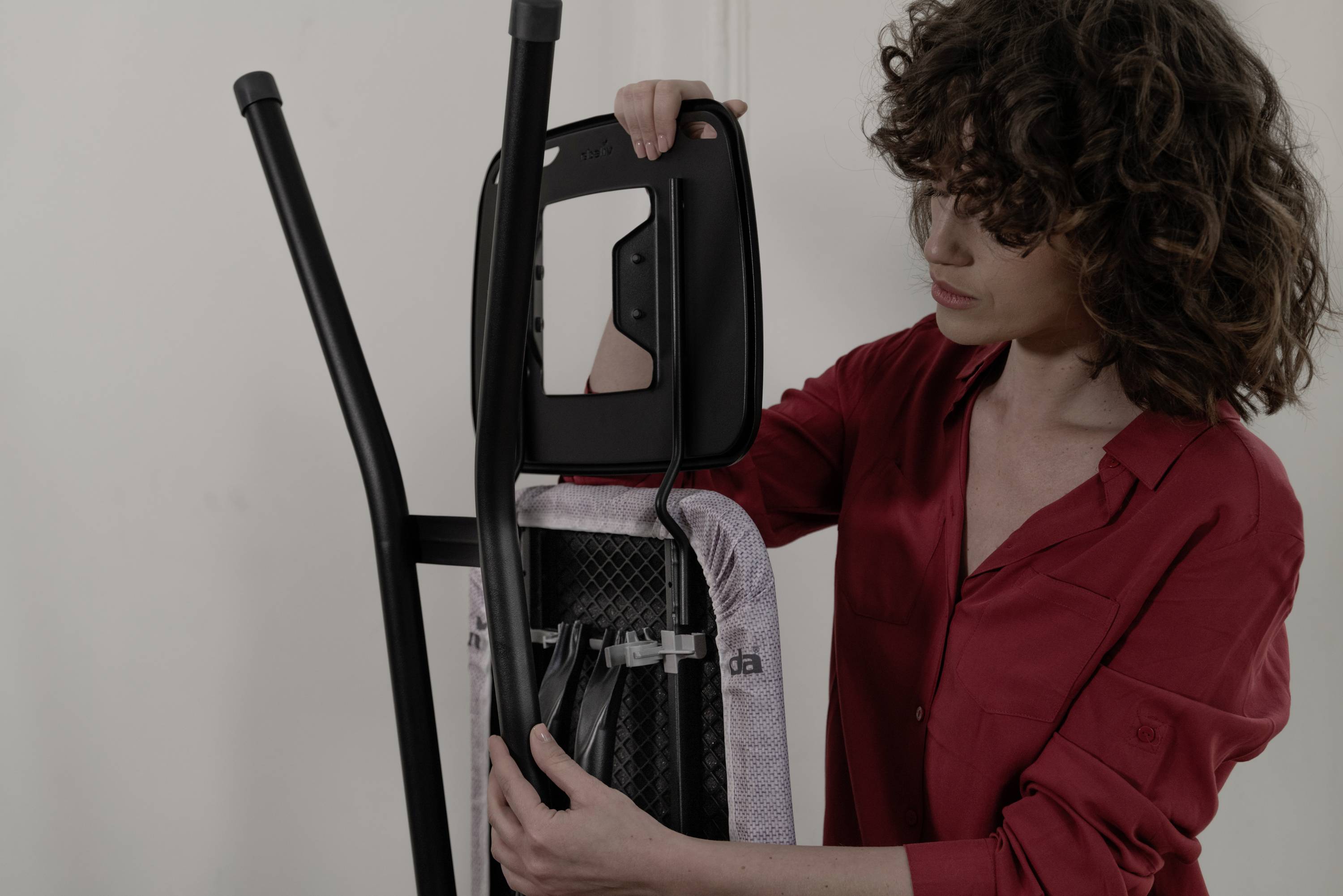 A person in a red shirt is assembling a chair by attaching the backrest.