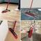 A broom with a red handle sweeps dust from wooden floors and carpets. The broom is also used for cleaning in the kitchen.
