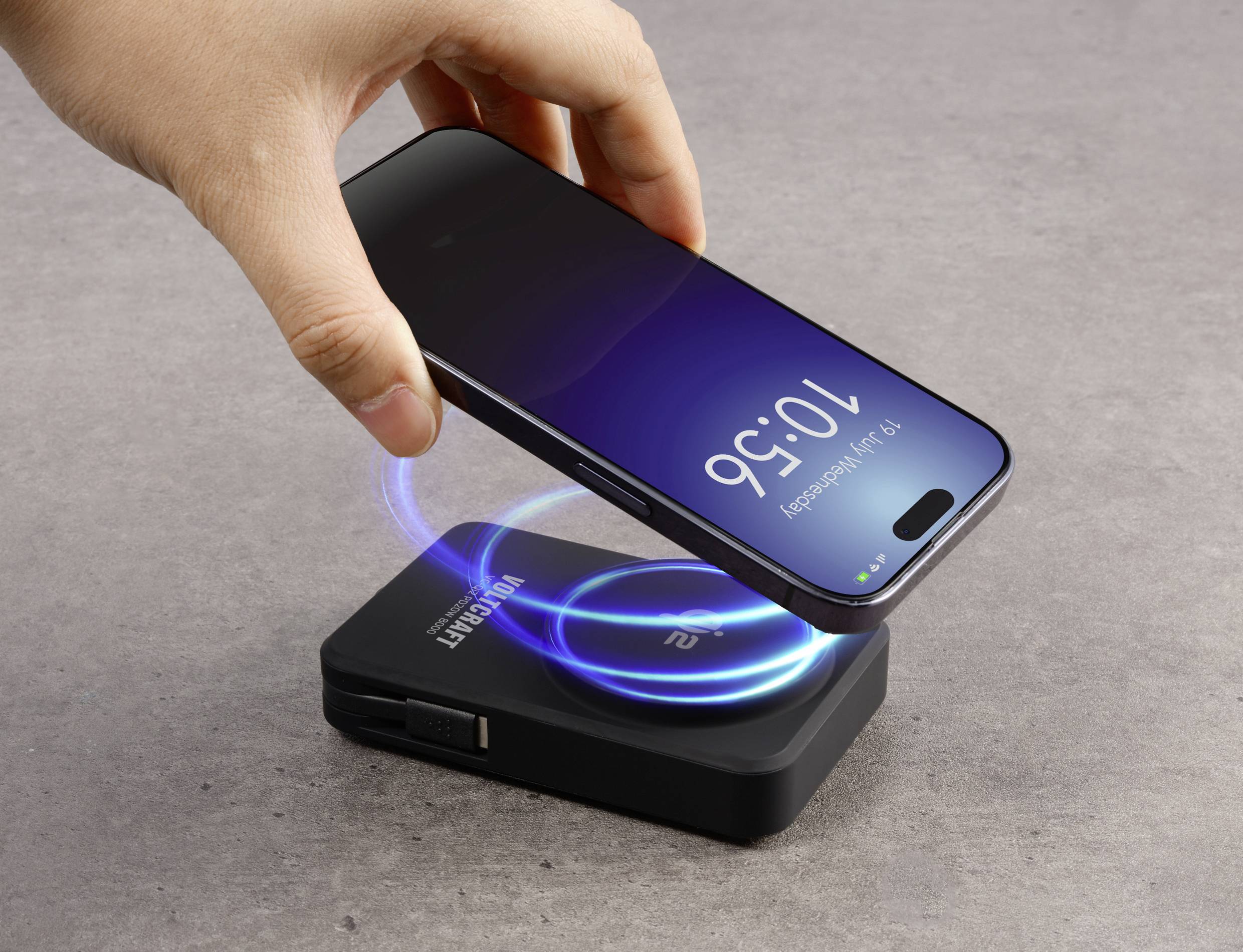 A smartphone is being held over a wireless charger displaying a blue charging indicator. The smartphone screen shows '10:56'.