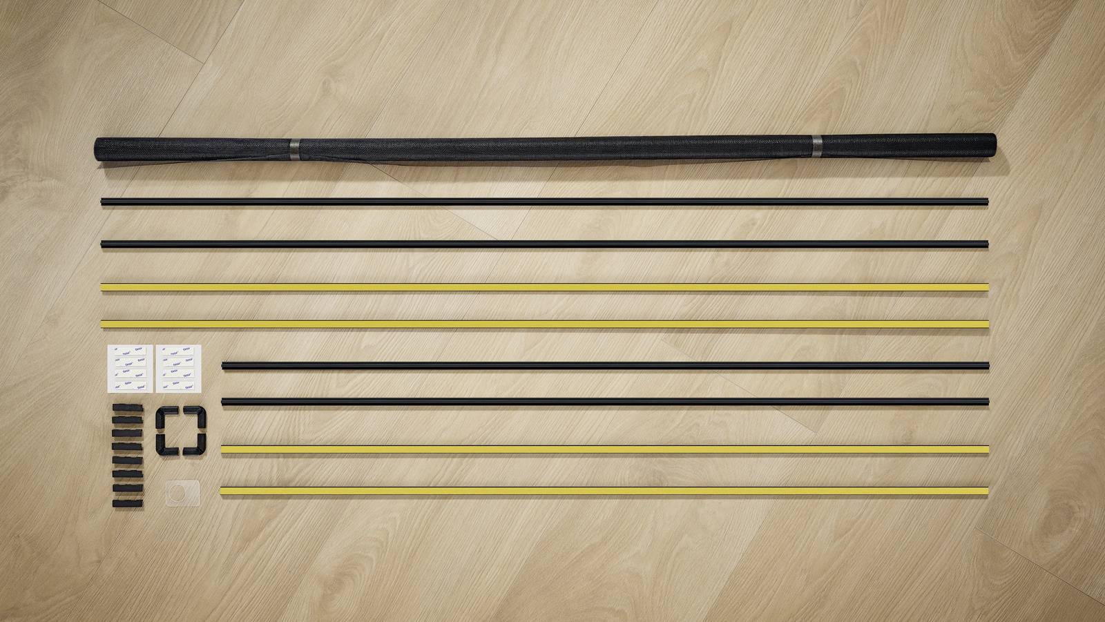 Several metal bars and accessory parts are lying on a wooden floor, arranged in preparation for assembling a structure.