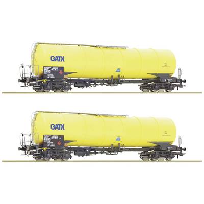Two yellow tank wagons on railway tracks, each with a 'GATX' logo. Both wagons are identical and are likely transporting liquids.