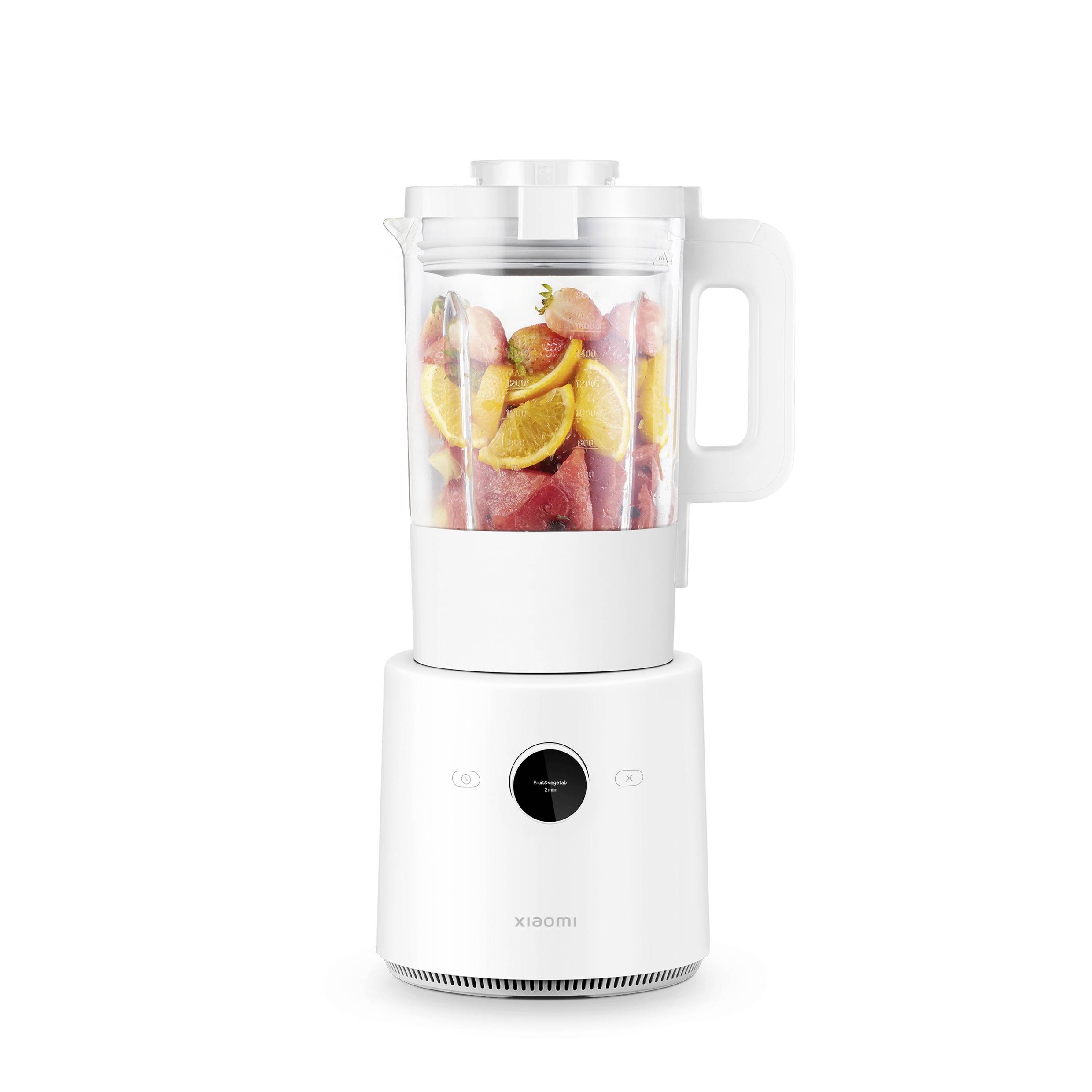 A white blender with a transparent jug, filled with sliced fruits such as strawberries and oranges, stands upright.