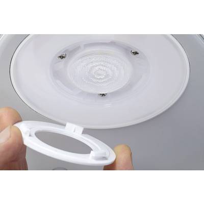 A person is holding a round plastic frame and installing it into a ceiling light that contains a circular LED lamp.