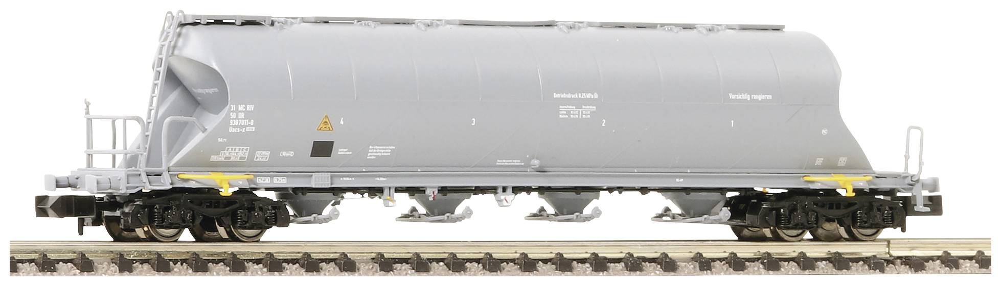 Grey freight train wagon on railway tracks, side view. The wagon has a rounded, enclosed container for transportation purposes.