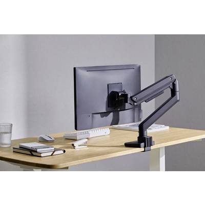 A tidy desk with a monitor on an adjustable arm, keyboard, mouse, notebooks, and a glass of water.