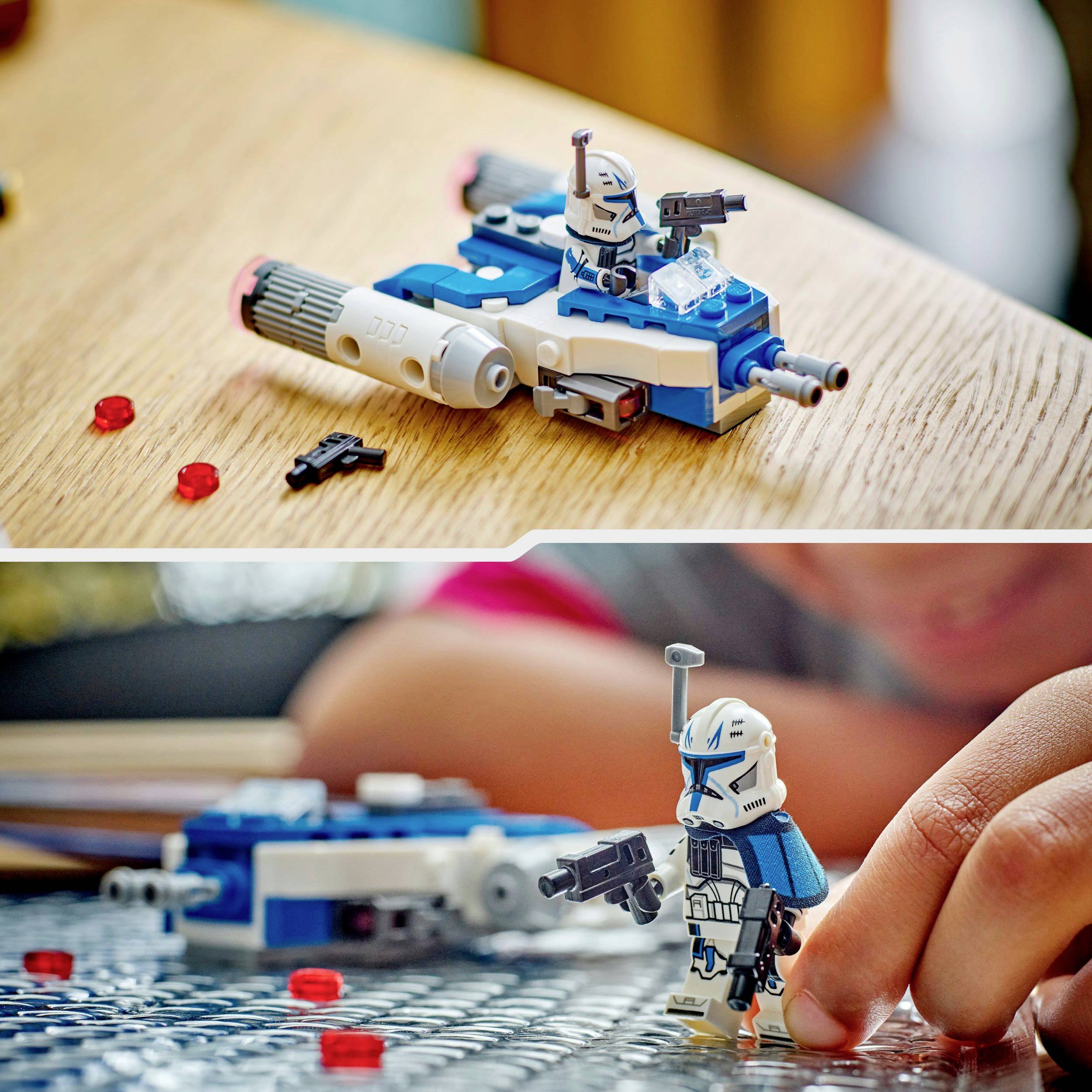 A person is playing with a Lego soldier and a small blue spaceship on a table. Red Lego bricks are scattered around.