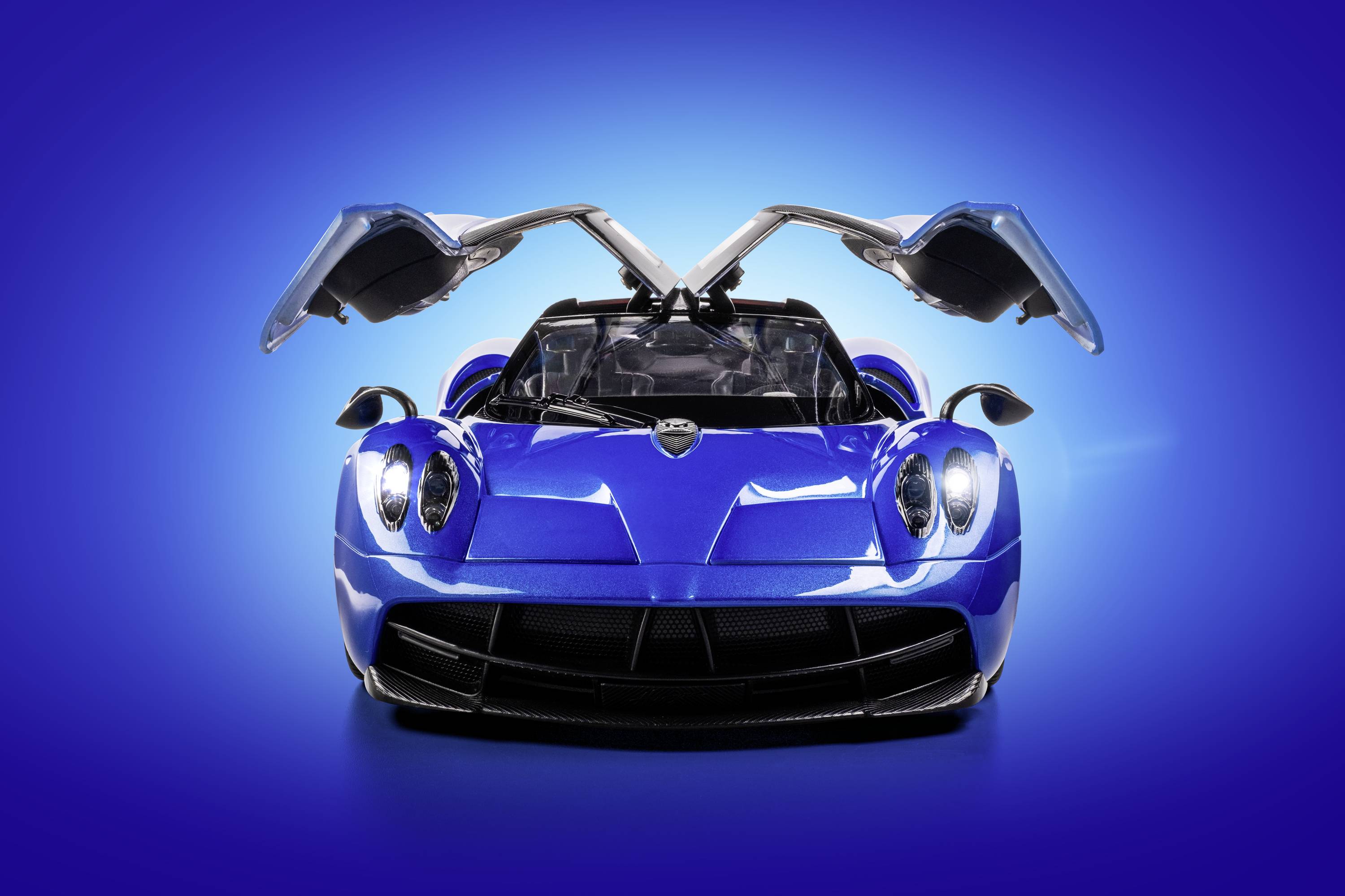 A blue sports car with open gull-wing doors against a light blue background, showcasing modern design and performance.