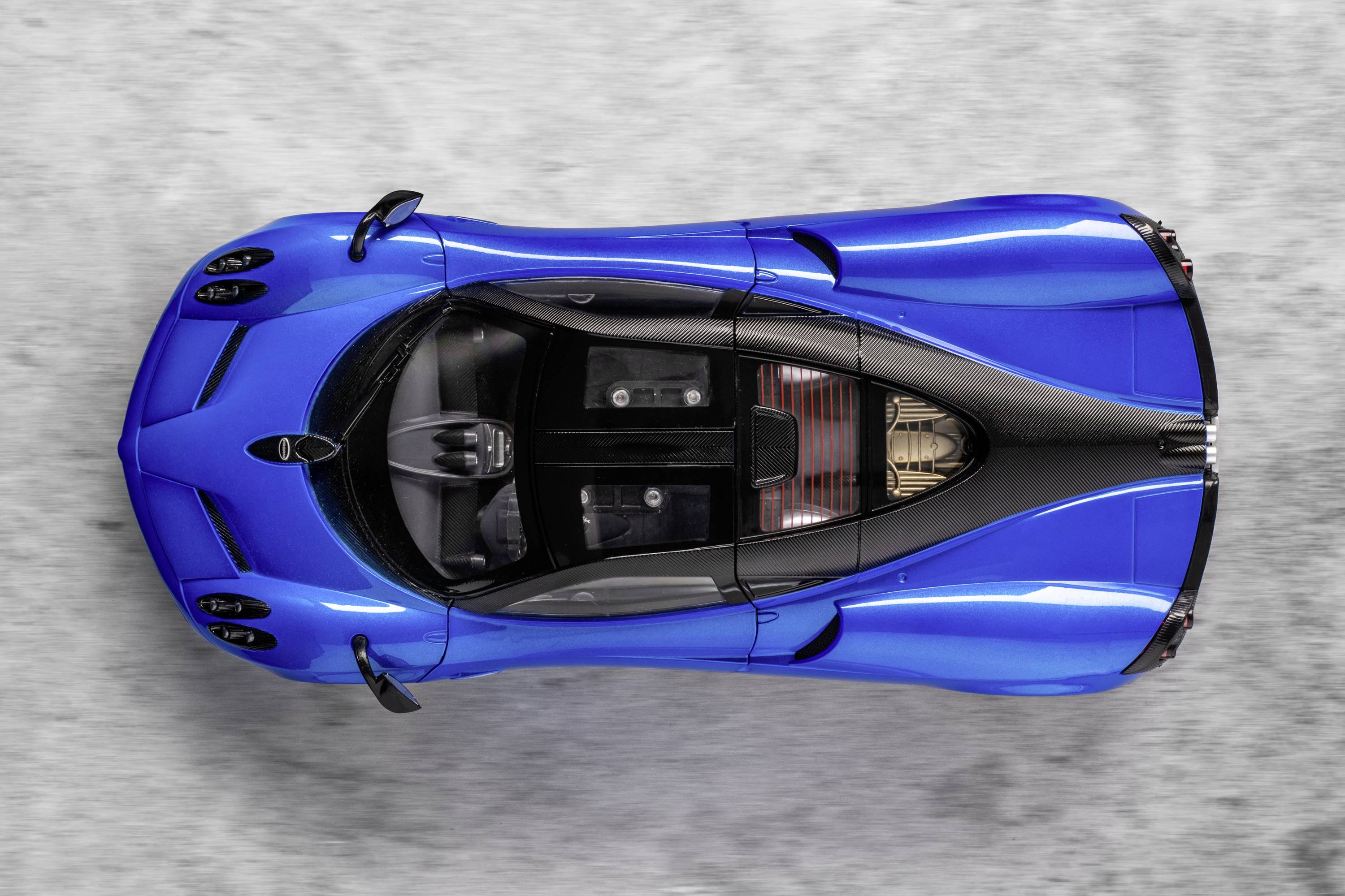 Blue sports car viewed from above on a grey background, showcasing elegant design and aerodynamic shape.