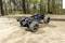 A remote-controlled car speeds along a forest path. Dust billows up behind its large tyres.