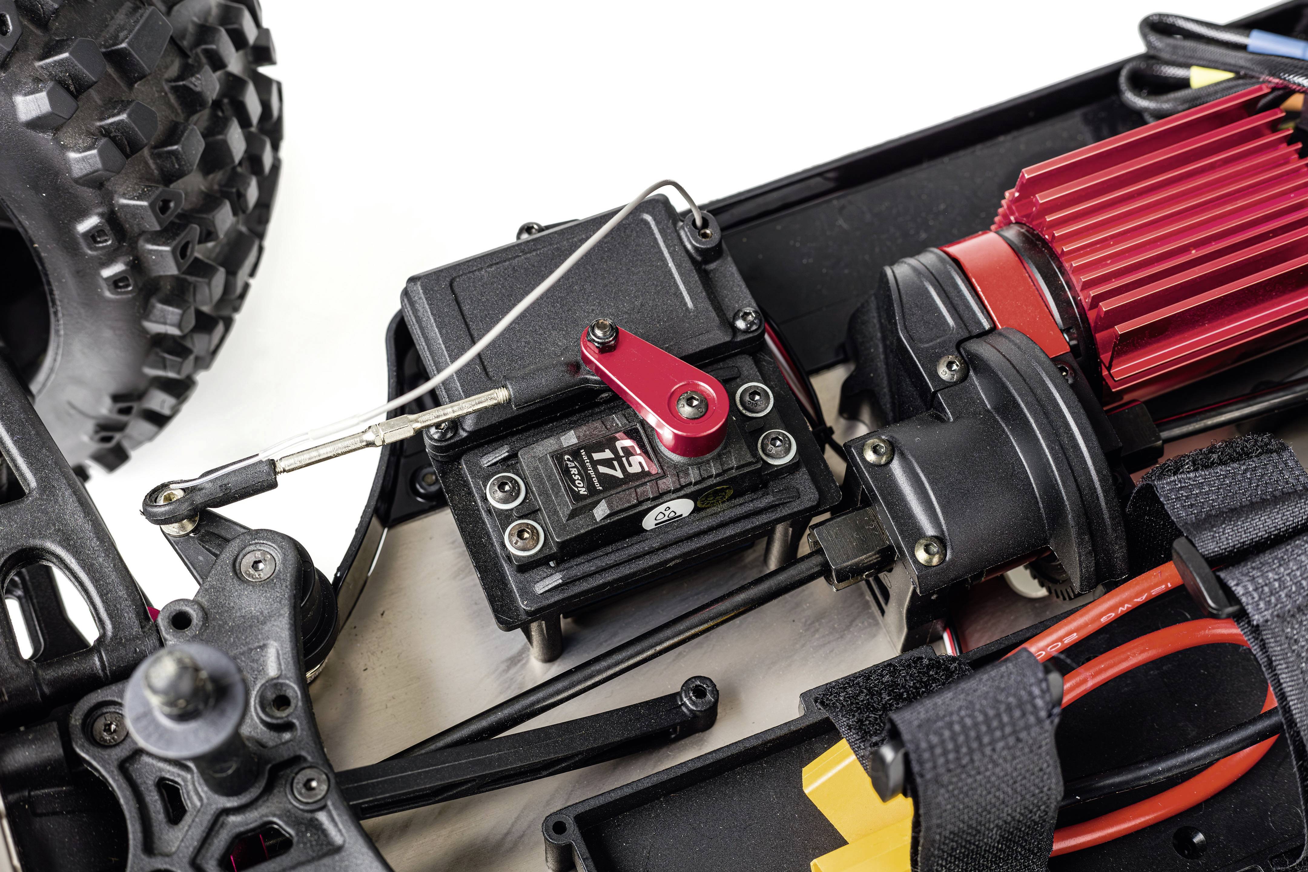 Close-up of a remote-controlled model car shows parts of the gearbox and engine with some cables and mountings.