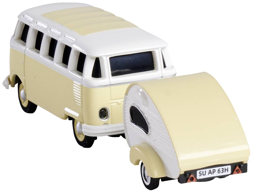 A cream-coloured toy bus is pulling a small caravan. Both objects have a nostalgic design.
