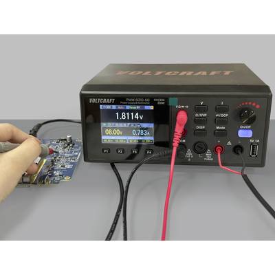 'A person is measuring the voltage on an electronic circuit board using a soldering iron. A measuring device is displaying various readings.'
