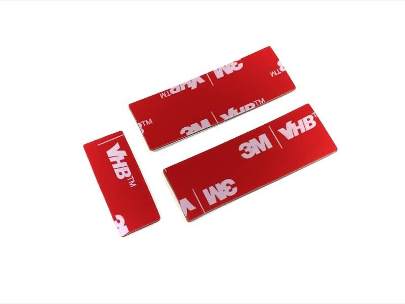 Three rectangular, red foam adhesive tapes with printed '3M VHB' logo.