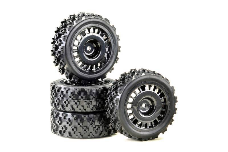 Two stacked and two leaned black, heavily treaded tyres for remote-controlled cars on a white background.