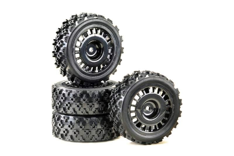Two stacked and two leaned black, heavily treaded tyres for remote-controlled cars on a white background.