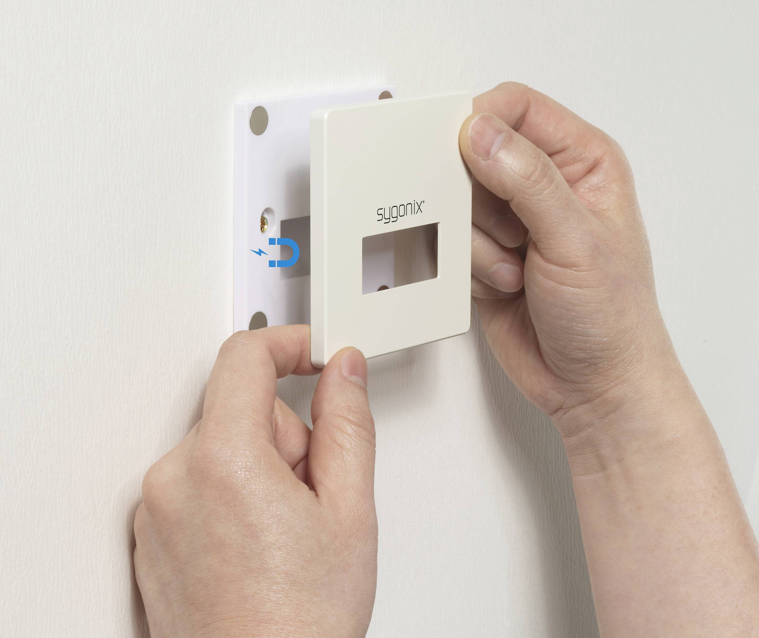 'A person is installing a white cover with a square opening over a socket strip on the wall.'