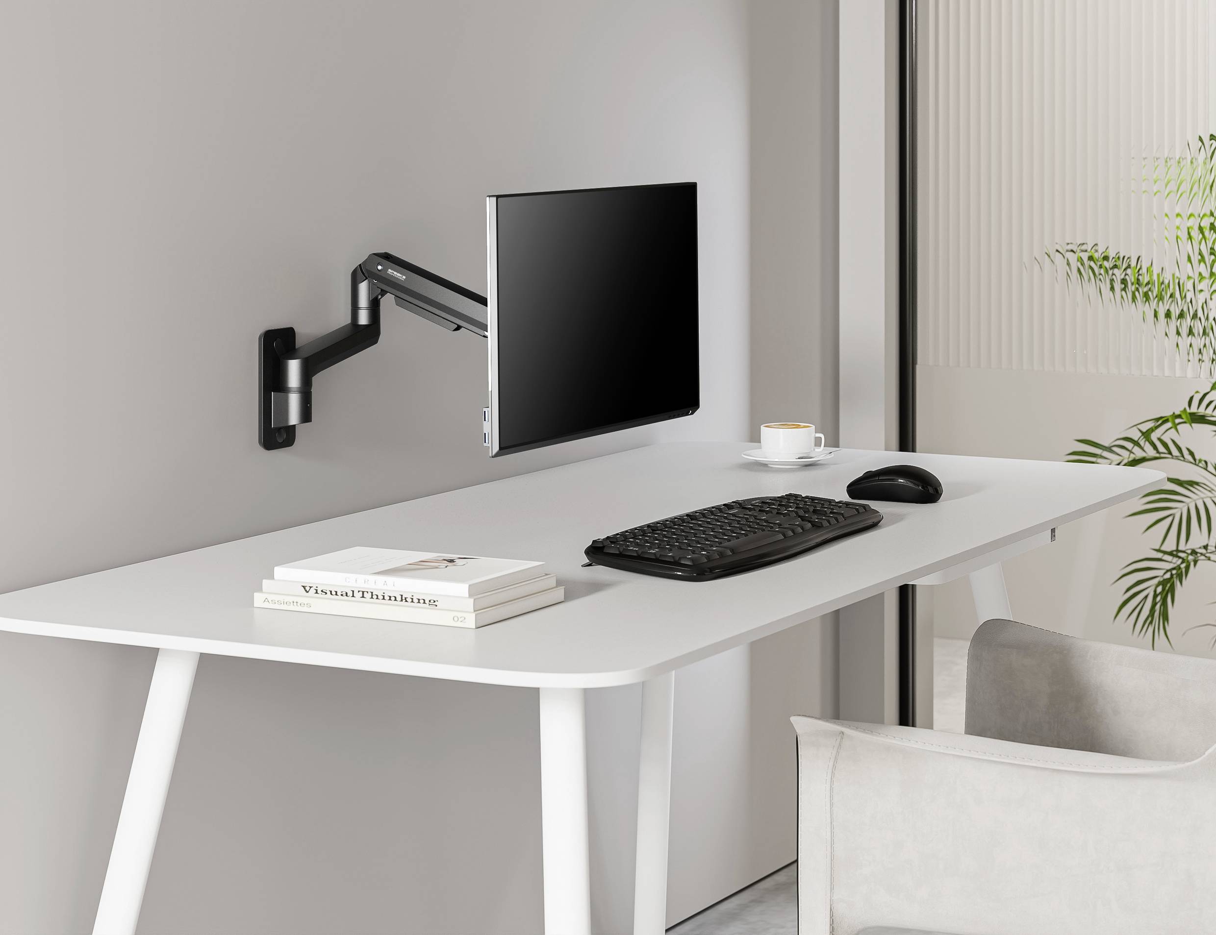 A modern desk with a wall-mounted monitor arm, on which a screen is suspended. Keyboard and mouse are placed on the desk.