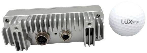 Grey technical device with two connections next to a golf ball bearing the inscription 'LUXonis'. Device has cooling fins.