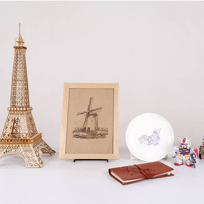 A table with a model of the Eiffel Tower, a picture frame featuring a windmill, a plate with a rabbit motif, and toy robots.