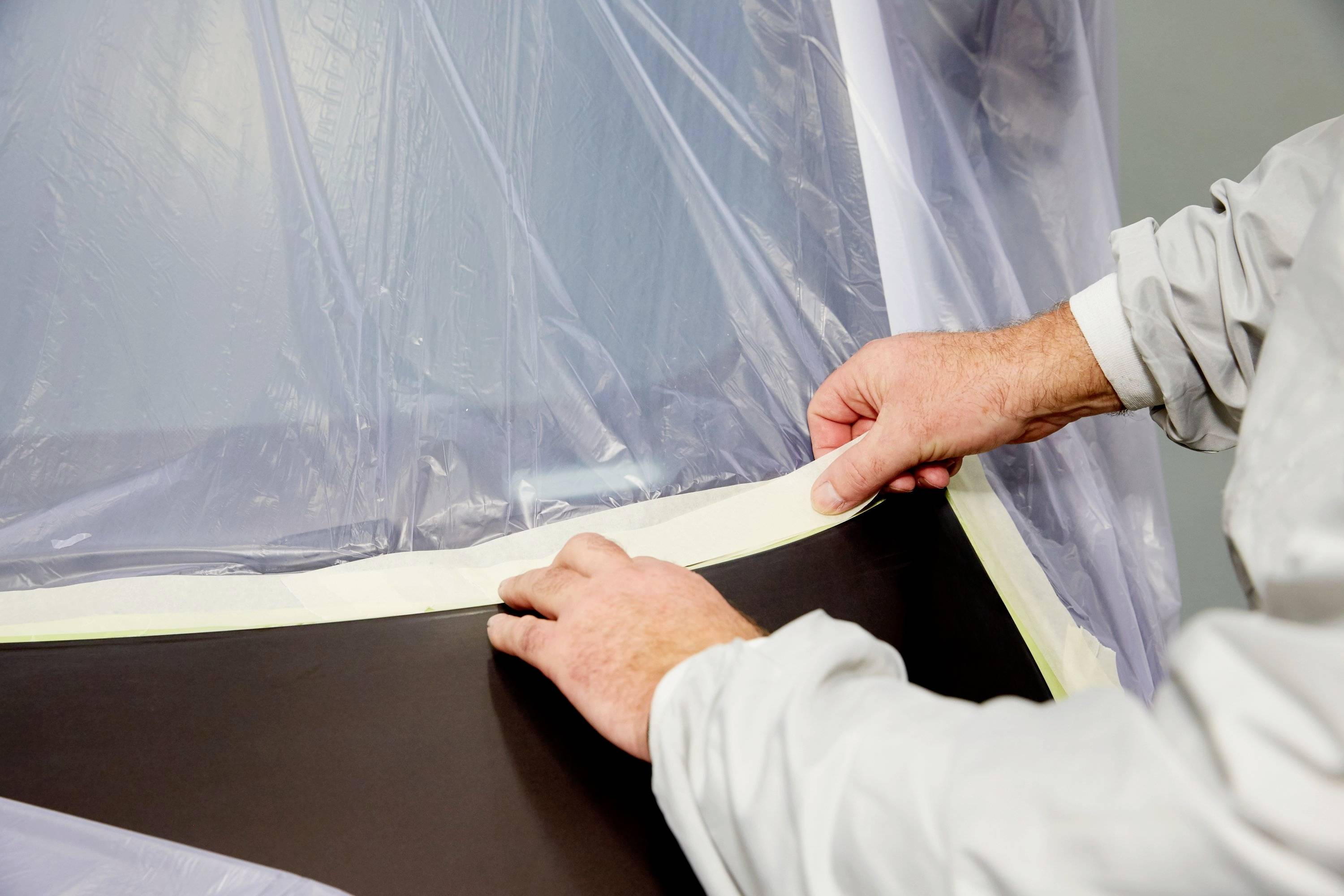 Hands of a man are sticking adhesive tape to the edge of a plastic cover.