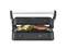A contact grill with an open lid grills meat and vegetables. The appliance has a dial for temperature adjustment.