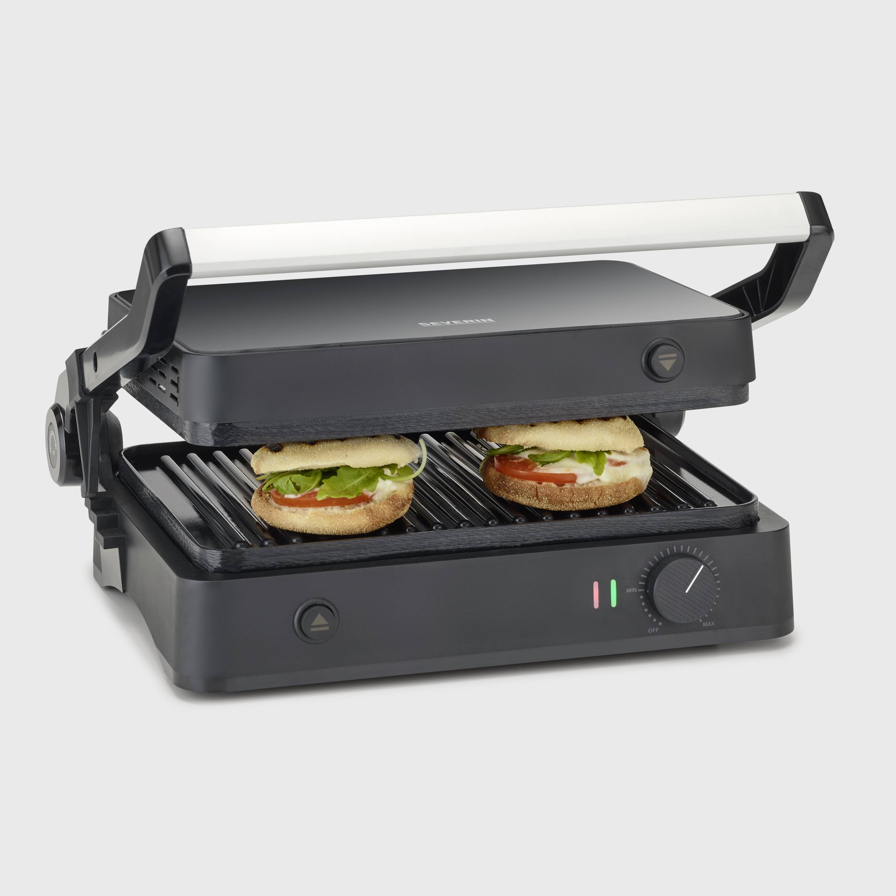 A black contact grill with two sandwiches being grilled inside. The grill has indicator lights and a temperature control dial.