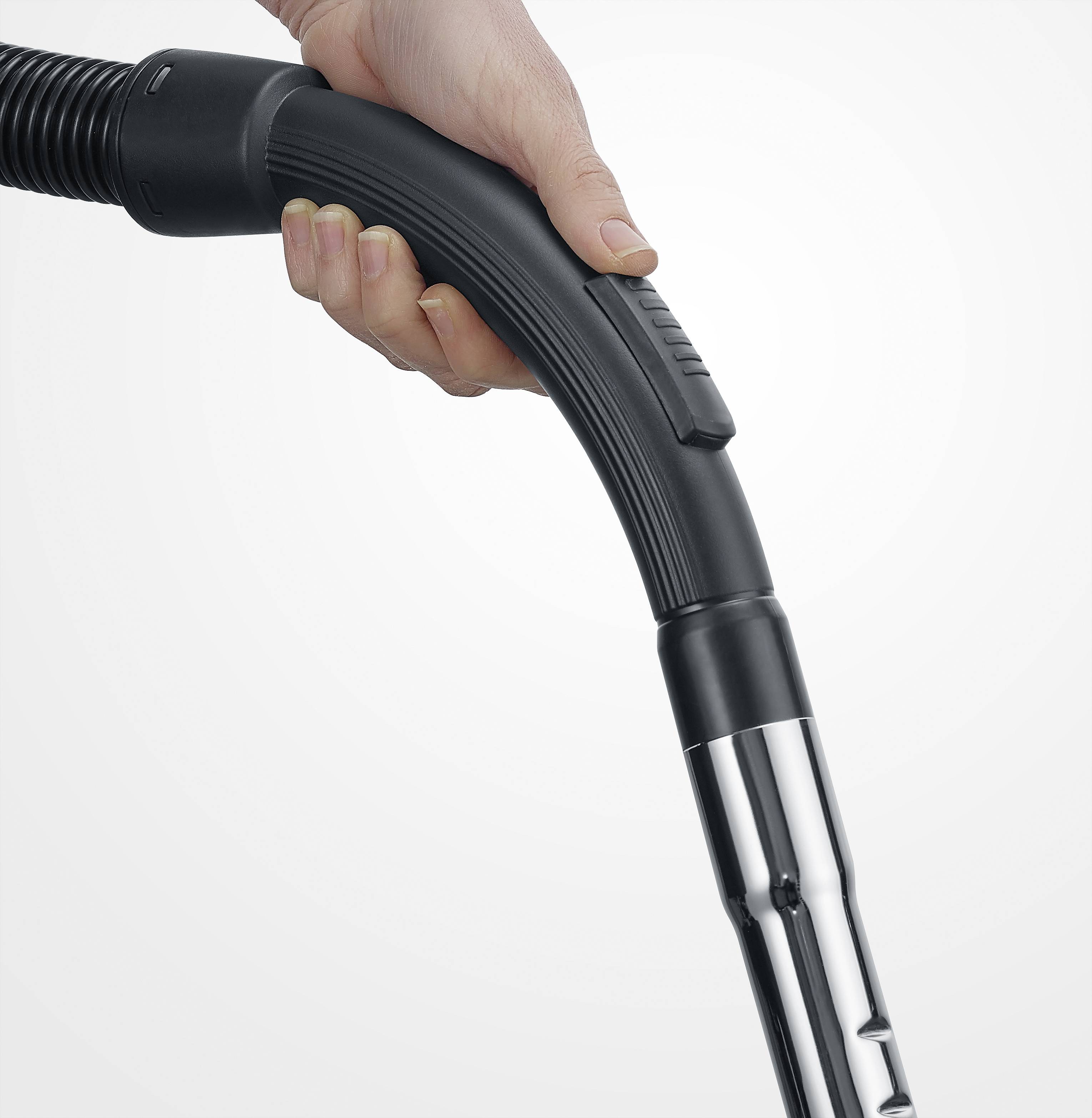 A hand is holding a black vacuum cleaner hose on a metal pipe.