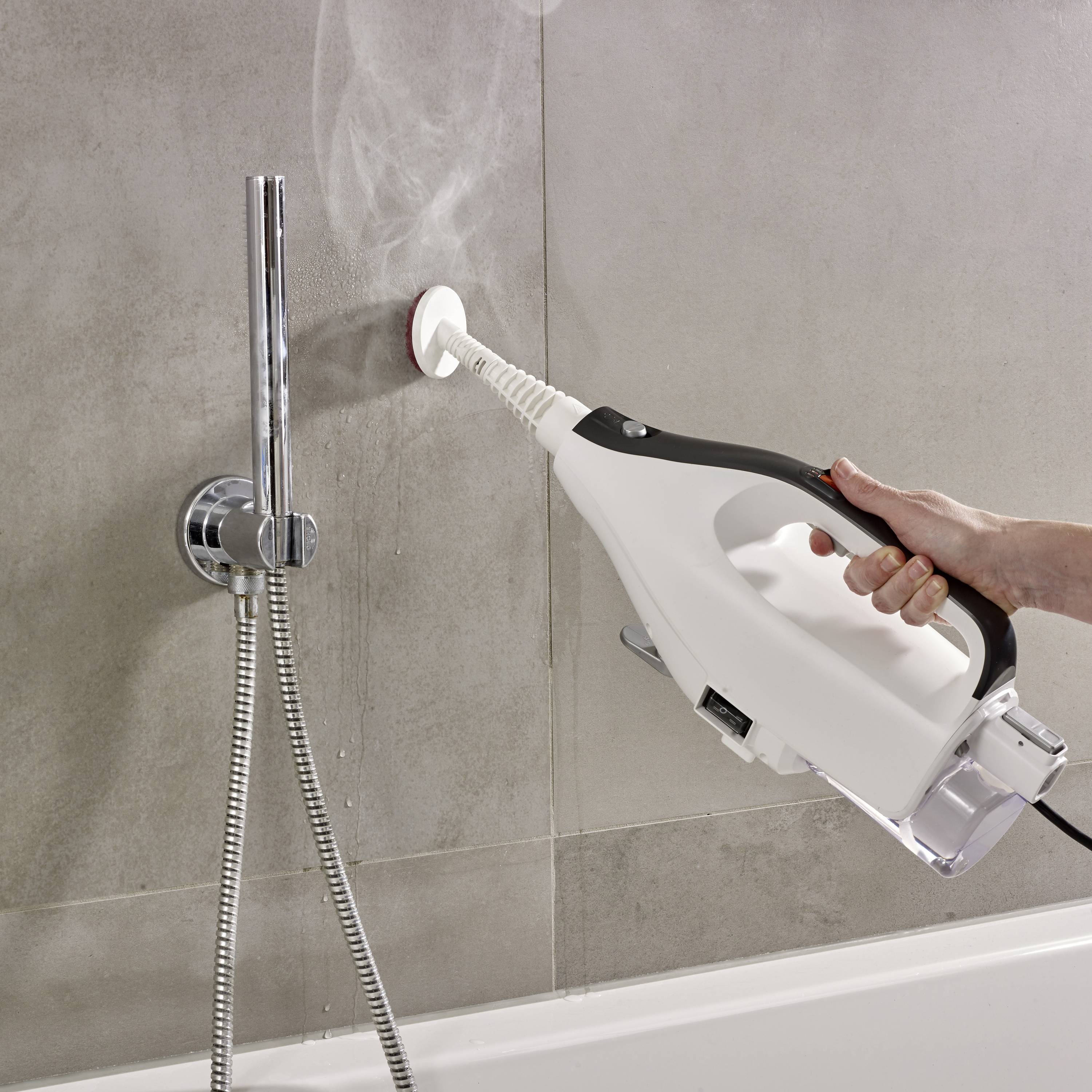 A person is cleaning grout tiles in a bathroom with a handheld steam cleaner to remove dirt and promote hygiene.
