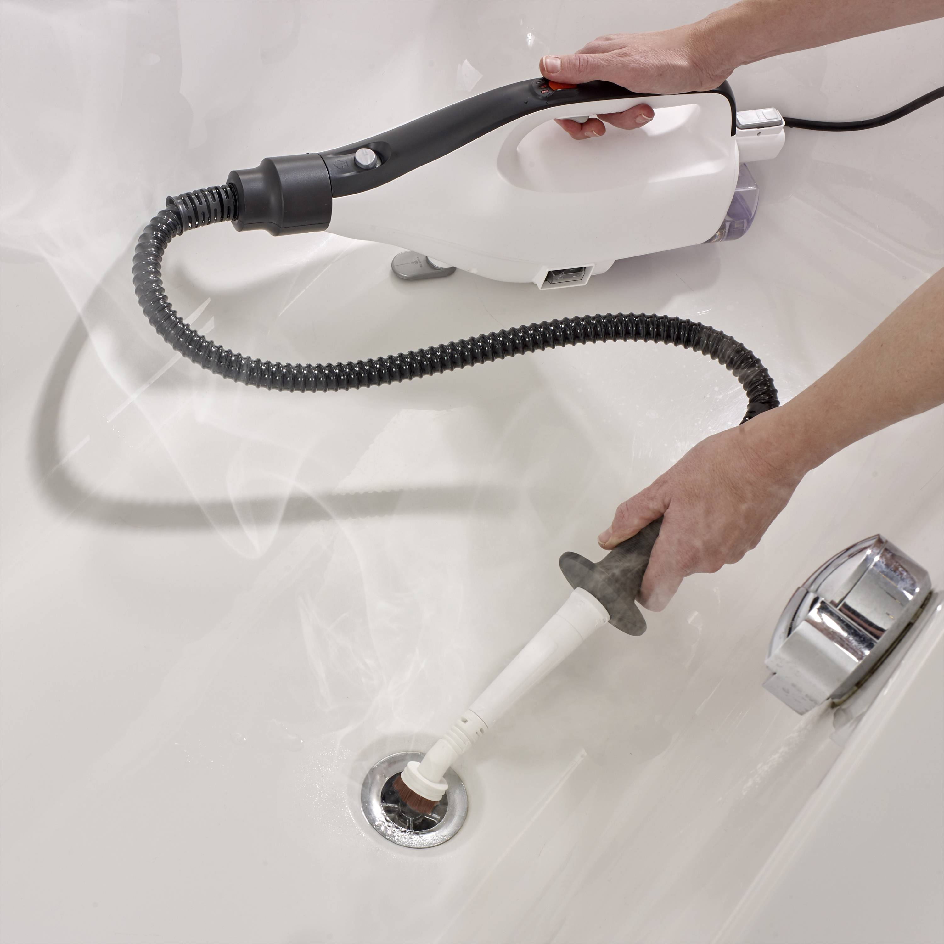 A person is cleaning a sink with a steam cleaner, focusing on the plughole. Steam rises into the air.