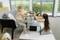 Two girls are sitting in a living room, happily playing a video game on a console, surrounded by modern furnishings.
