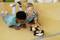 Two boys are carefully watching a small toy car approaching a target line on a wooden surface.
