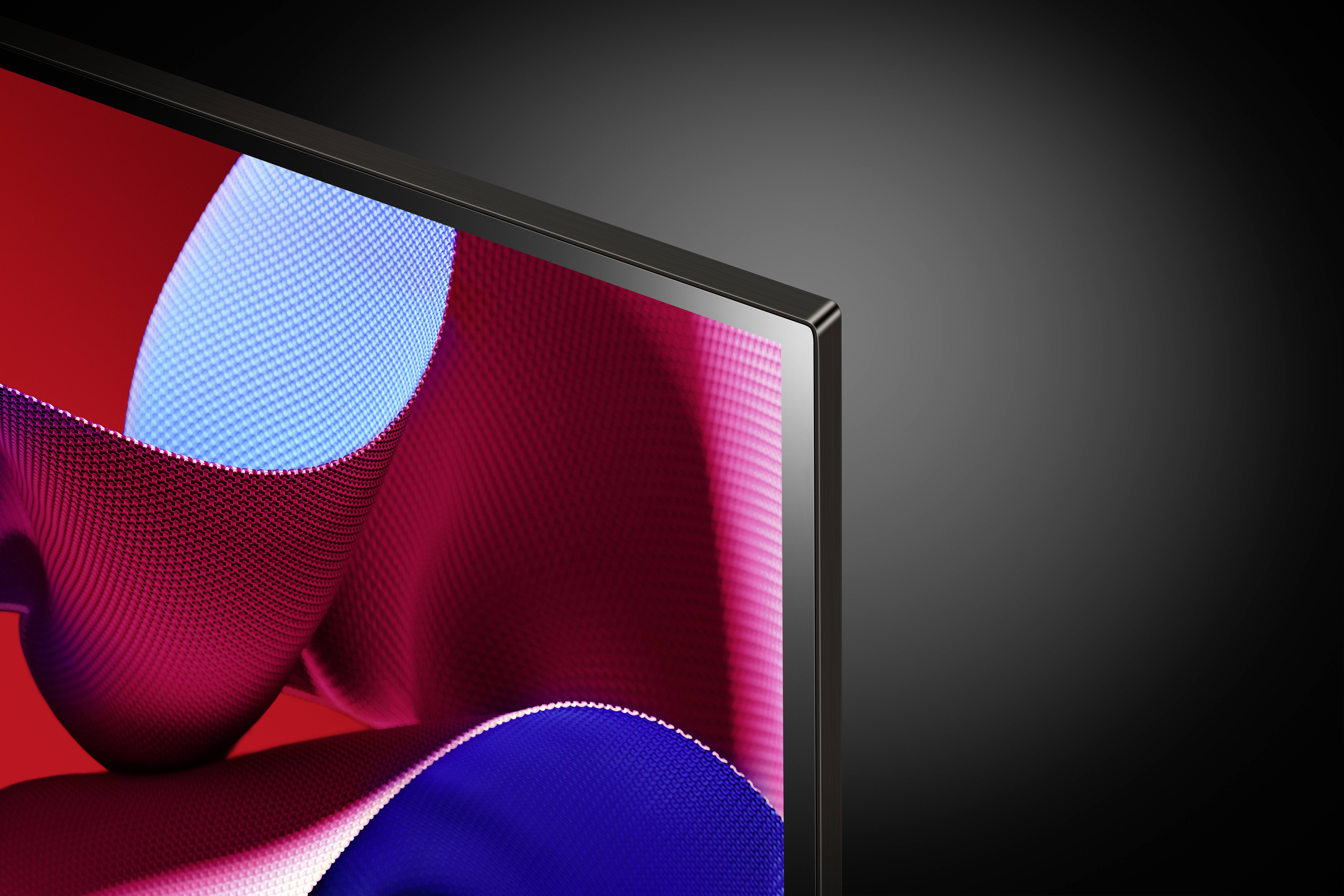 Close-up of a modern computer monitor corner against a black background, displaying an abstract red and blue screen background.