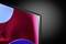 A flat screen in the corner of an image displays an abstract pattern in red and blue tones against a dark background.