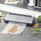 A vacuum sealer on a kitchen worktop is sealing a piece of salmon in plastic. Surrounded by vegetables and spices.