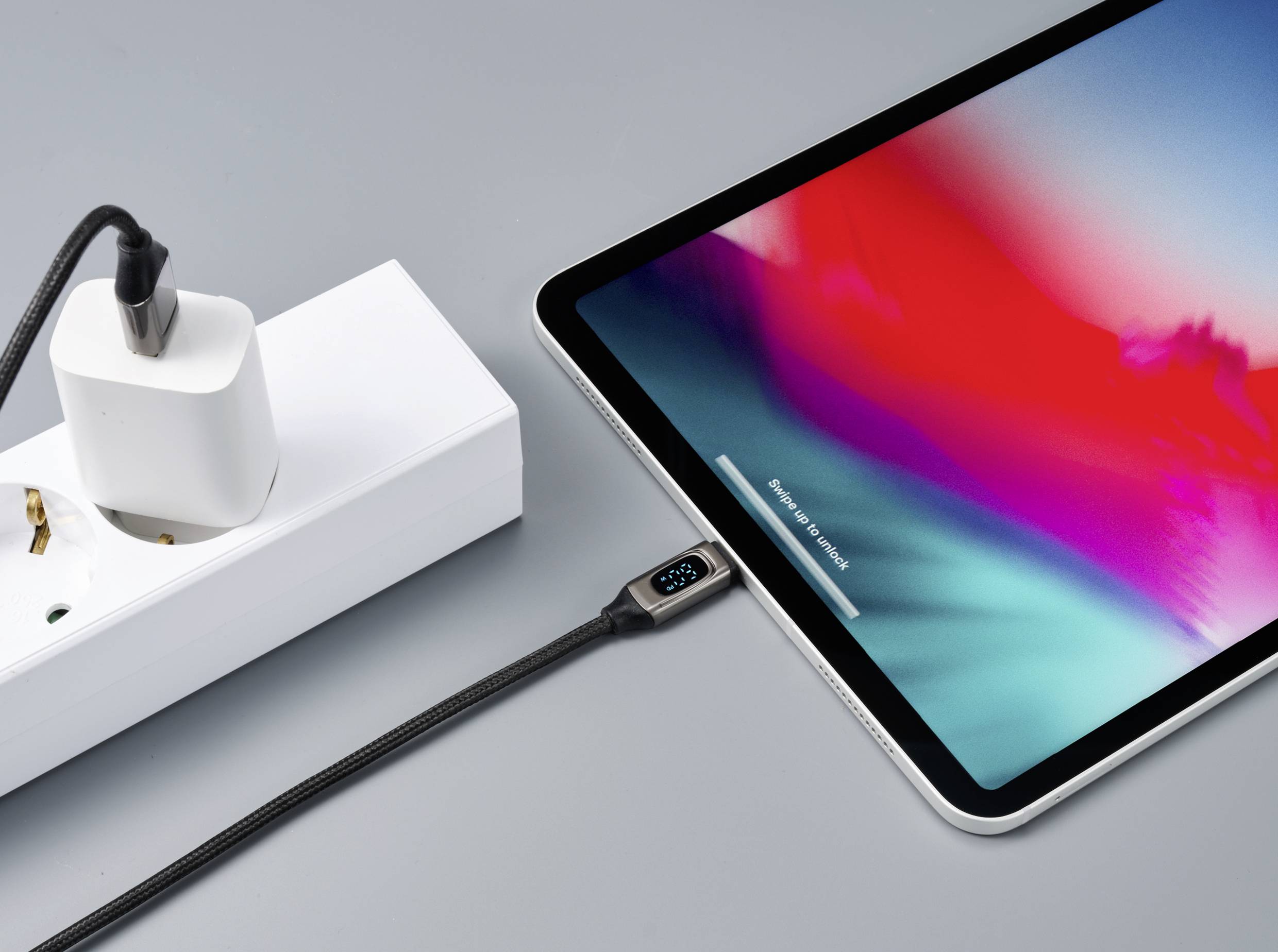 A tablet is being charged with a charging cable connected to a power socket. A charging status indicator on the cable shows 92%.